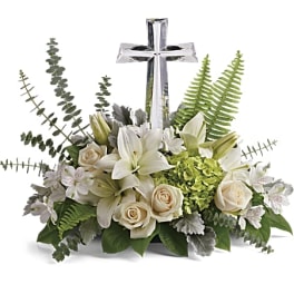 White lilies and roses arranged around a silver cross