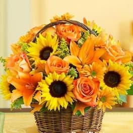 Basket arrangement of sunflowers, orange roses, and lilies