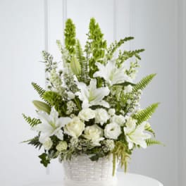 White lilies and roses in a white basket arrangement