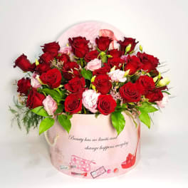 Red and pink roses arranged in a pink round gift box