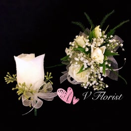 White rose boutonniere and matching wrist corsage with white ribbons on a black background.