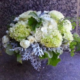 White and pale green floral arrangement in a clear vase