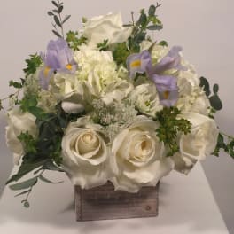 White rose and hydrangea arrangement with lavender irises in a wooden box