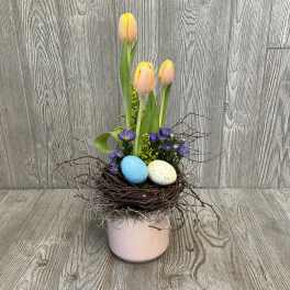 Tulips and purple flowers in a pink pot with decorative eggs