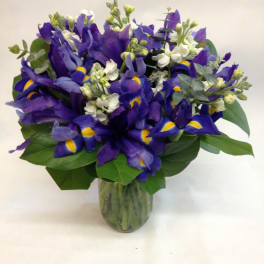 Purple iris bouquet in a glass vase with white accent flowers