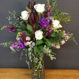Bouquet of white roses and purple flowers in a glass vase