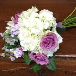 Hand-tied bouquet of white hydrangeas with purple roses and light lavender accent flowers