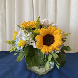 Sunflower and mixed daisy bouquet in a glass vase