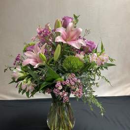 Pink lilies and roses arranged in a clear glass vase
