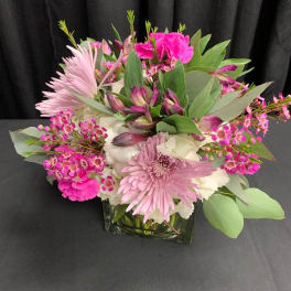 Pink and white mixed flower arrangement in a square glass vase