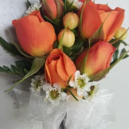 Small bouquet of orange roses with white filler flowers and a white ribbon