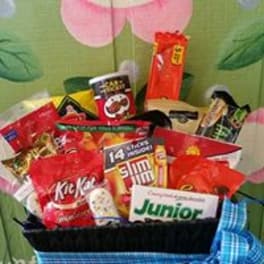 Basket of assorted candy bars and snacks with a blue ribbon