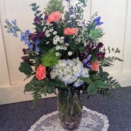 Tall mixed flower arrangement in a glass vase