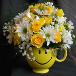 Yellow smiley-face mug holding yellow roses and white daisies