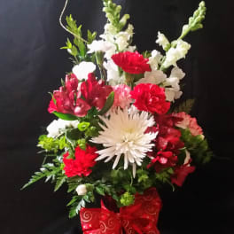 Red and white mixed flower arrangement in a red ribboned container