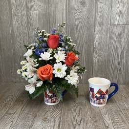 Bouquet of roses and daisies in a printed mug, with a matching mug beside it