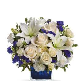 White lilies and cream roses arranged in a blue glass vase