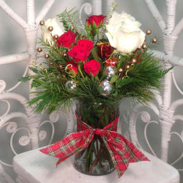 Red and white roses in a glass vase with a plaid ribbon