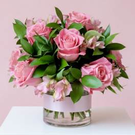 Pink roses arranged in a clear glass vase with green foliage