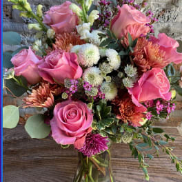 Pink roses and mixed blooms arranged in a glass vase