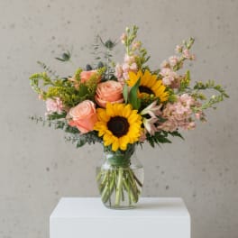 Bouquet of sunflowers and peach roses in a clear glass vase