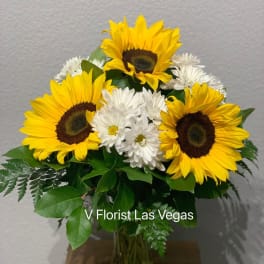 Medium vase arrangement of yellow sunflowers and white daisies in a clear glass vase