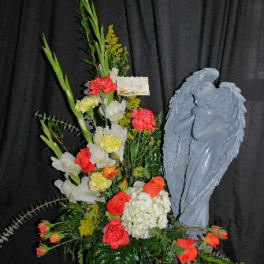 Standing floral spray with red, white, and yellow flowers beside a blue angel figure