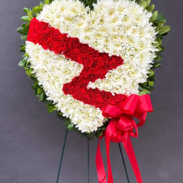 Heart-shaped floral wreath with red ribbon on a stand