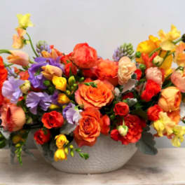 Colorful bouquet of mixed flowers in a white bowl vase