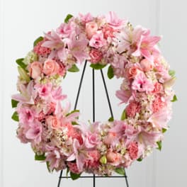 Pink floral wreath on a black metal stand