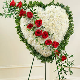 Heart-shaped floral spray with red roses and white flowers on a stand