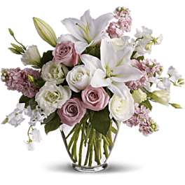 Pink and white roses with lilies in a clear glass vase