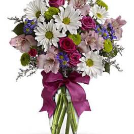 Bouquet of daisies, roses, and alstroemeria in a glass vase with a pink ribbon