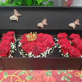 Red roses arranged in a black gift box with butterfly decorations