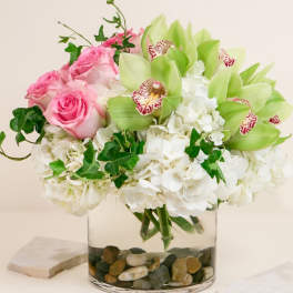 Pink roses and white hydrangeas with green orchids in a glass vase