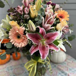 Mixed bouquet with pink lilies, roses, and gerbera daisies in a glass vase