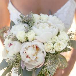Bride holding a white bouquet of peonies and roses