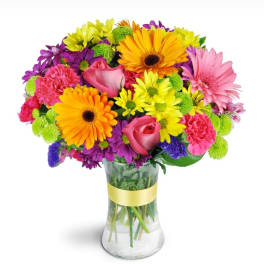 Colorful bouquet of gerbera daisies, roses, and carnations in a glass vase