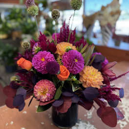 Bright mixed bouquet in a black vase with pink, orange, and purple blooms