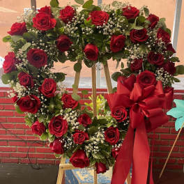Heart-shaped wreath of red roses with a large red bow