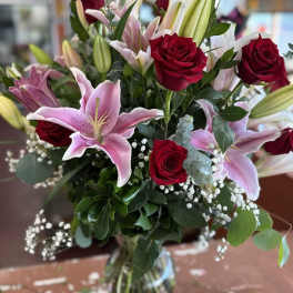 Bouquet of red roses and pink lilies in a glass vase