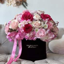 Pink and white rose bouquet in a black hat box with a ribbon