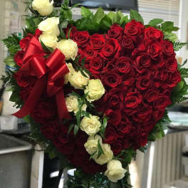 Heart-shaped bouquet of red and white roses with a red ribbon