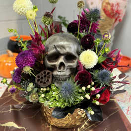 Skull centerpiece with purple and white flowers in a gold vase