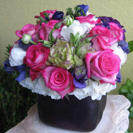 Pink and white roses with purple blooms in a black vase