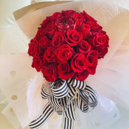 Bouquet of red roses wrapped in white paper with a striped ribbon