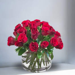 Compact arrangement of red roses in a clear glass cylinder vase