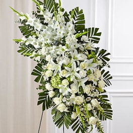 Large white funeral spray with lilies and roses on a stand