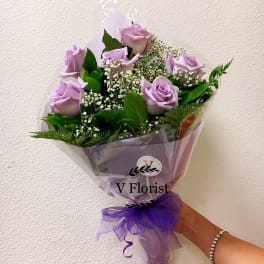 Lavender rose bouquet wrapped in purple paper with a ribbon