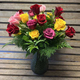 Mixed roses in red, pink, and yellow arranged in a dark vase